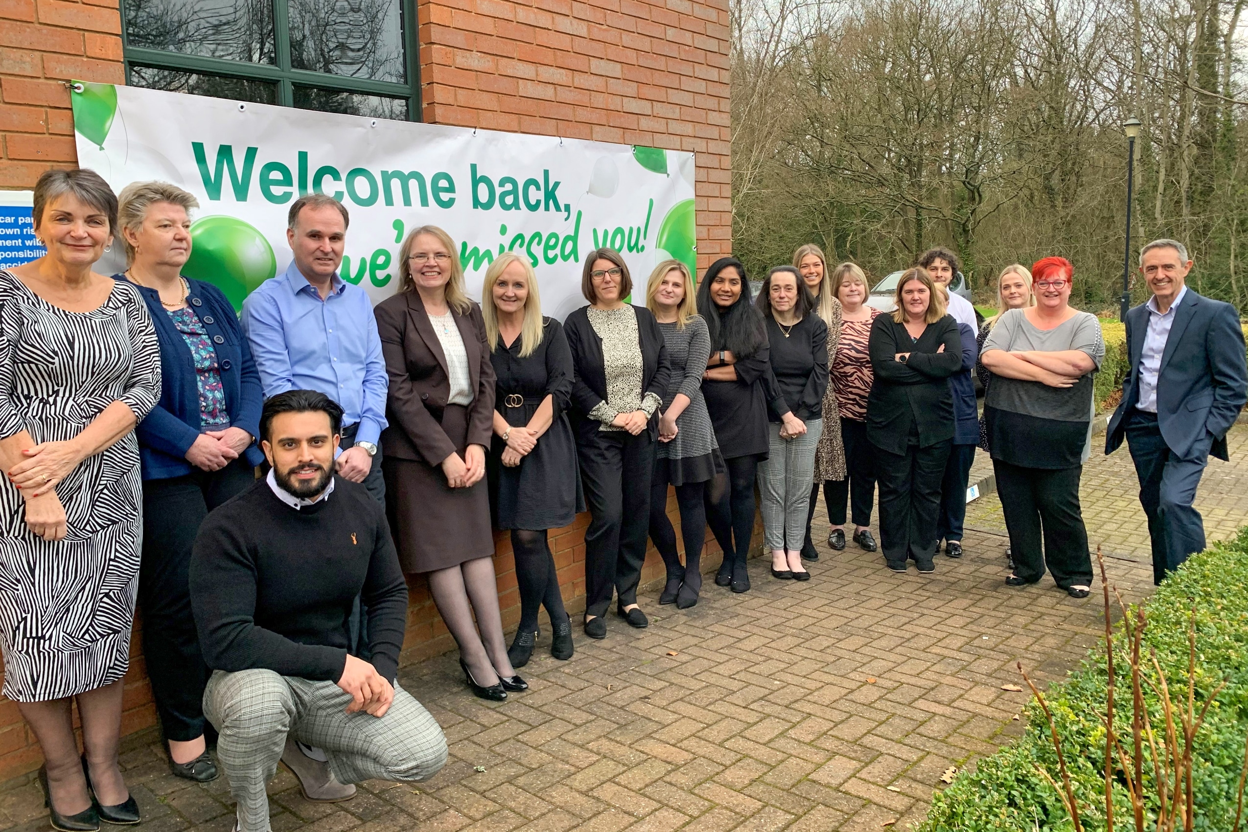 The first members of the Healthcare Management Solutions team to return to the company's head office with a giant welcome back banner.